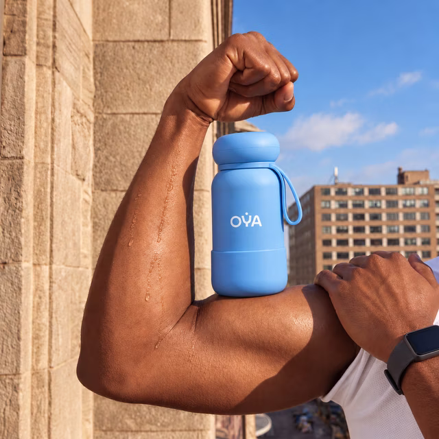 A flexed arm with the OYA bottle resting on it