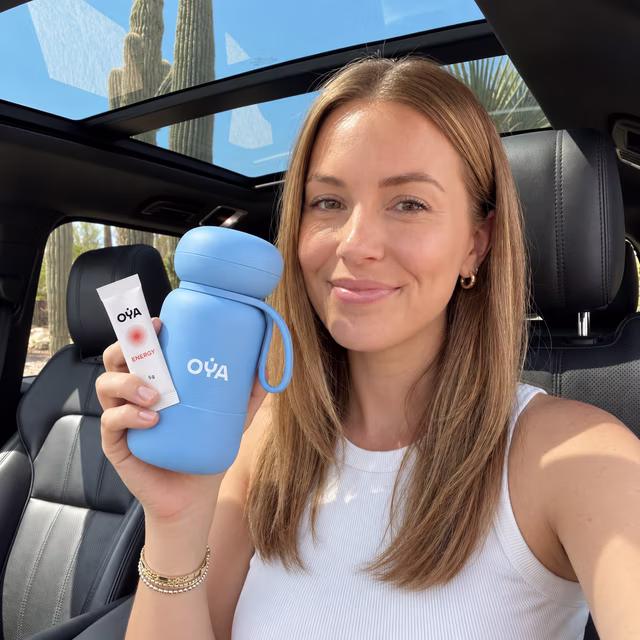 A woman in a car, the OYA bottle and a stick in hand